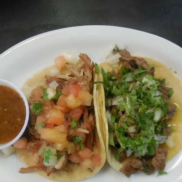 Two La Fuente Mexican Restaurant tacos, one with carnitas and pico de gallo, the other with carne asada.