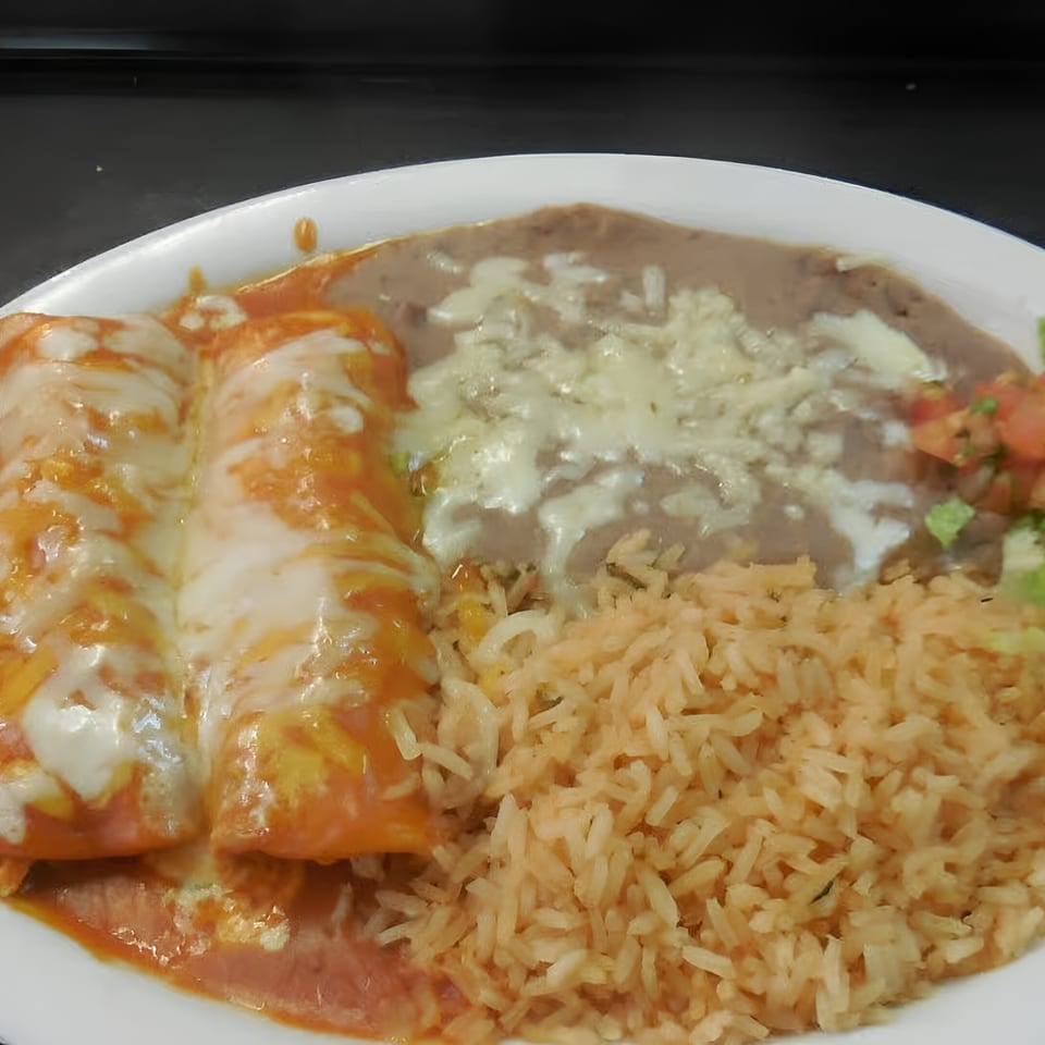 Two cheese enchiladas with red sauce, rice, and refried beans with melted cheese on a white plate.